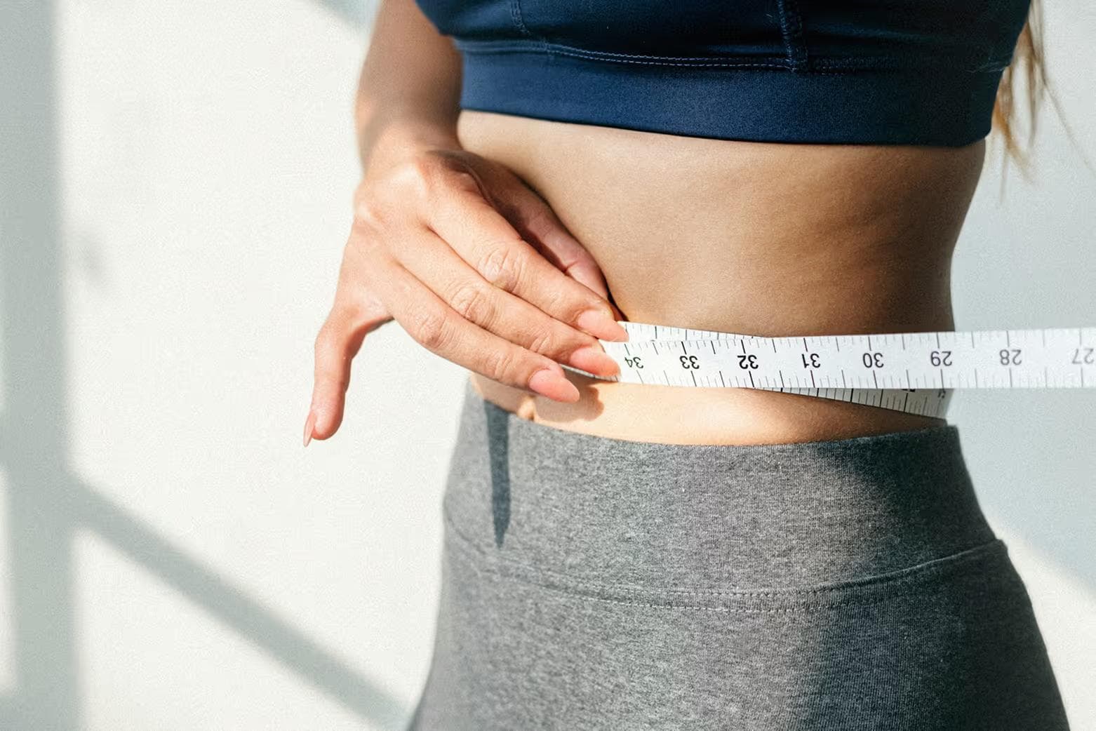 Person measuring their waist with a tape
